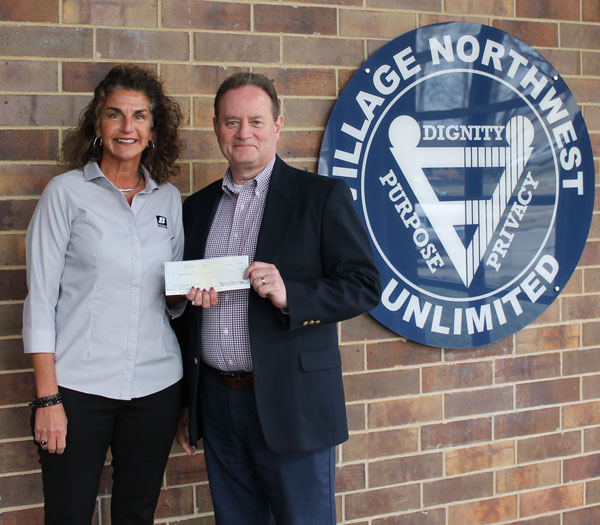 Barry Whitsell receiving $1,000 donation check from Heidi Brown and Shazam for Village Northwest Unlimited